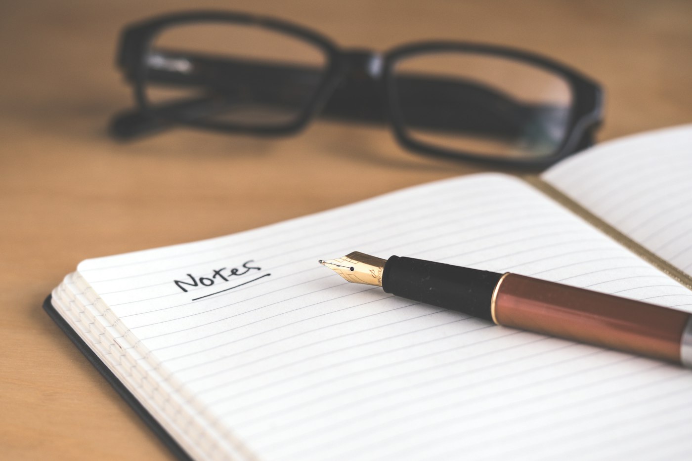 Notebook, pen and reading glasses on a desk